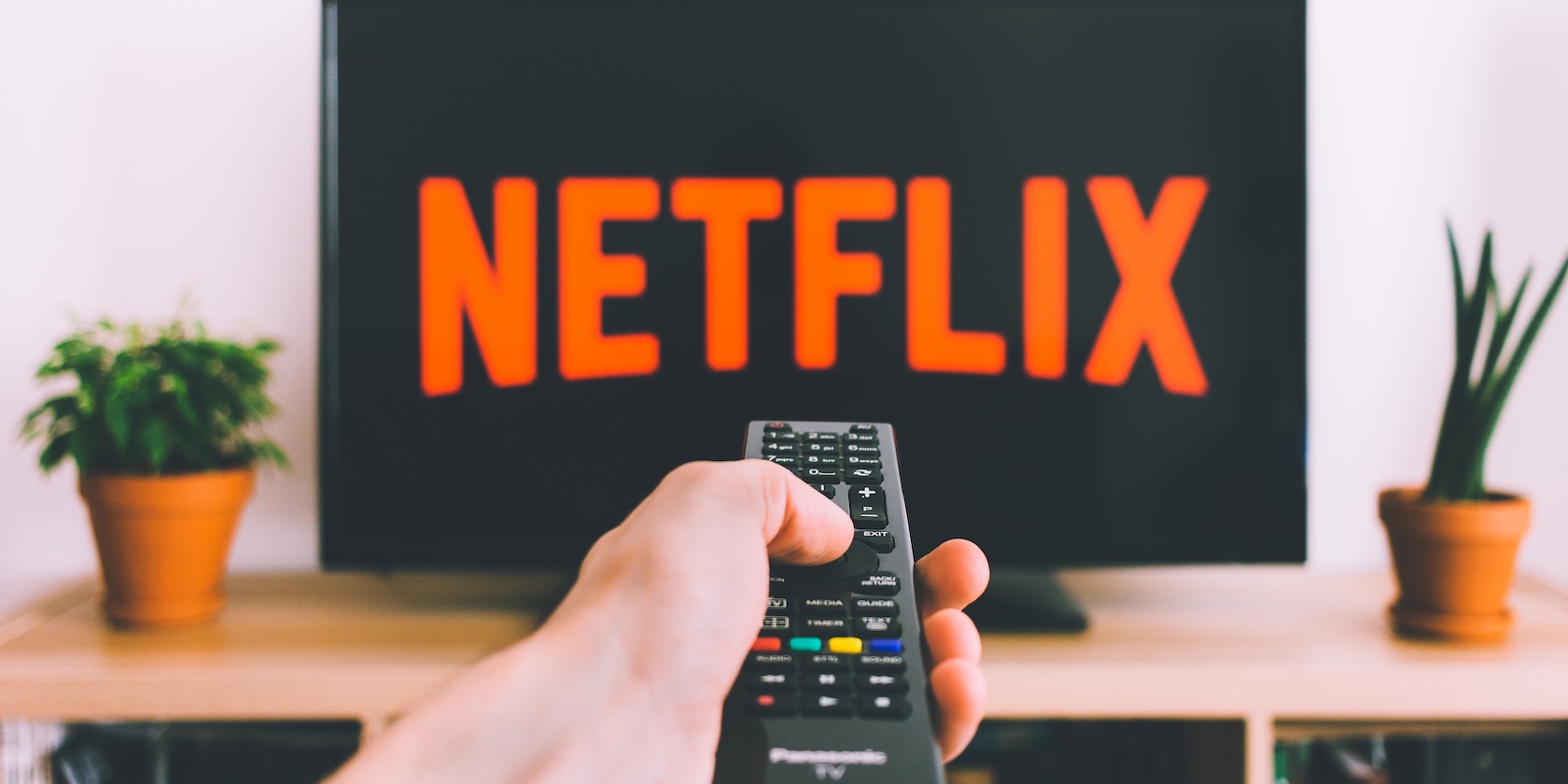 Guy pointing remote at Netflix on TV