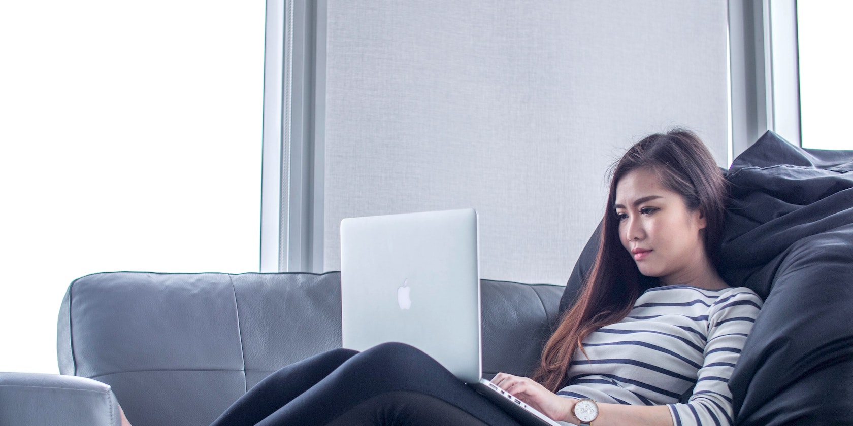 Woman sitting on couch and typing on a MacBook